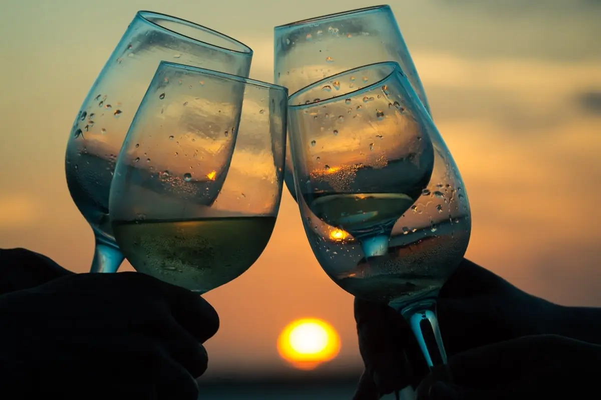 Sunset on sea between raised wine glasses